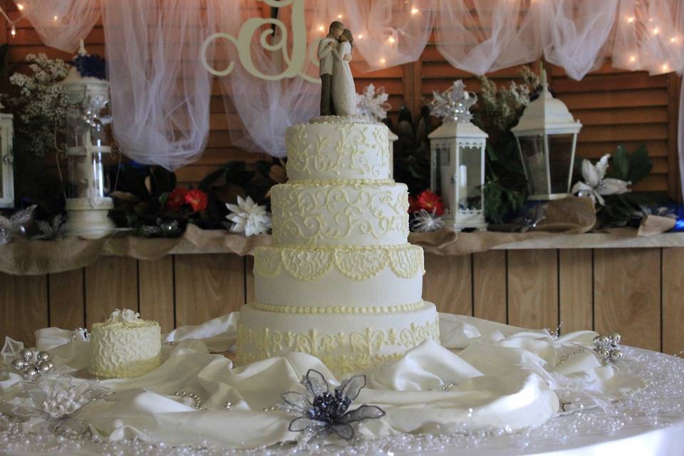 Very elegant 4 tier white cake, buttercream icing with the  design in light cream color, with the 1st anniversary on the side