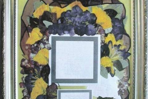 artistically arranged bouquet flowers surrounding invite and response card, envelope and boutonniere on bottom right on iridescent yellow satin