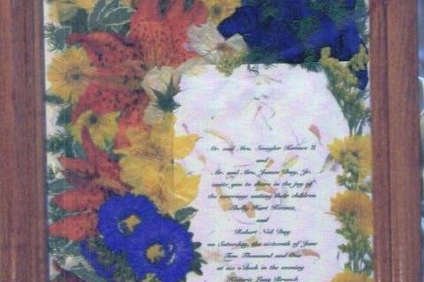 handmade invite surrounded by orange lilies, blue delphinium and yellow carnations