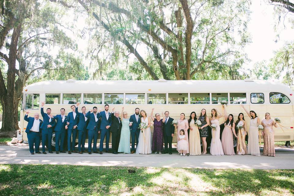 Newlyweds and their wedding guests by the bus