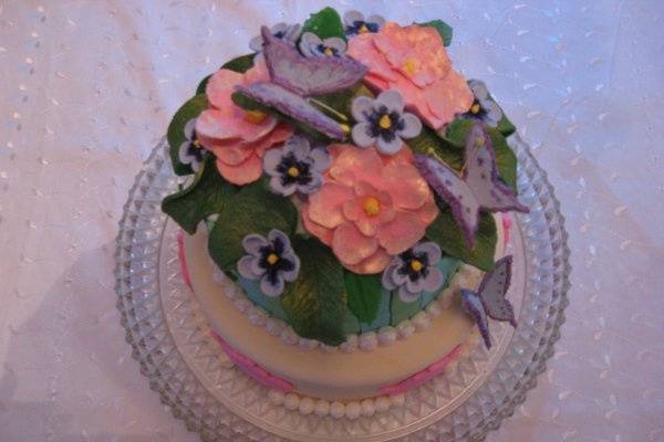 Garden Wedding Cake, sugar paste flowers and butterflies, with pearlized royal icing for a boarder and fondant cut-outs. The cake is a white and chocolate marble cake with chocolate moose filling. Cost: $260