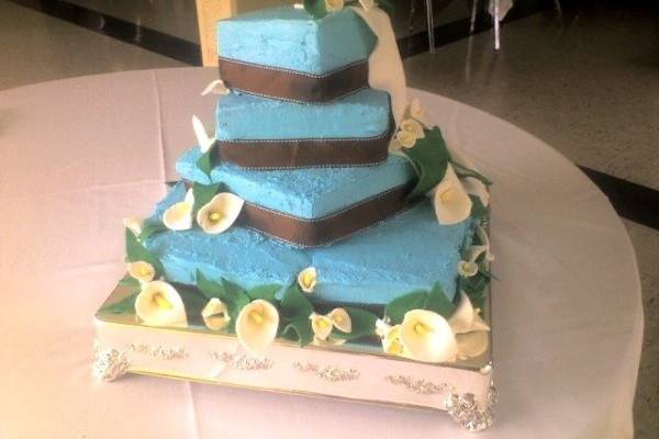 Sugar Calla lilies and leaves with a white fondant drape. The ribbon was provided by the bride to match her bridemaid's dresses. The cake is a buttercream frosting cake. Cost: $475