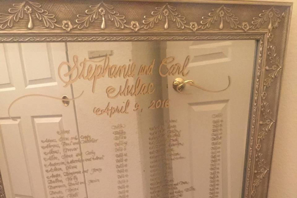 Seating chart drawn with hand calligraphy lettering on a five foot tall mirror with gold paint.