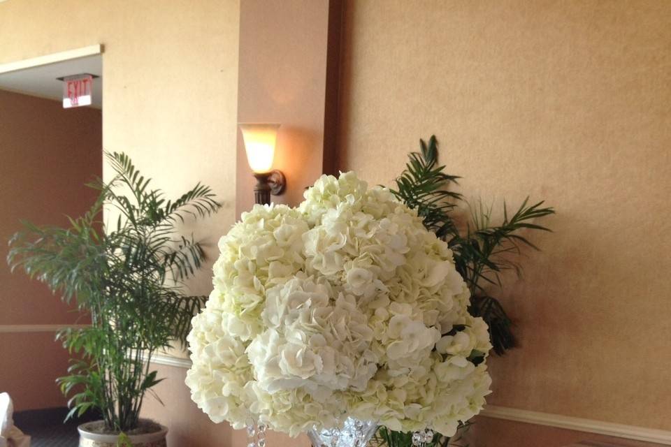 Tall footed glass containers with hanging crystals and a ball of hydrangeas