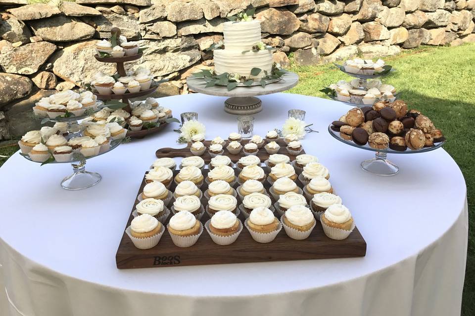 Wedding cake and wedding cupcake display.  Rustic outdoor reception.  Cupcakes are mix of carrot, lemon ginger, and vanilla in both regular sizes and mini's.