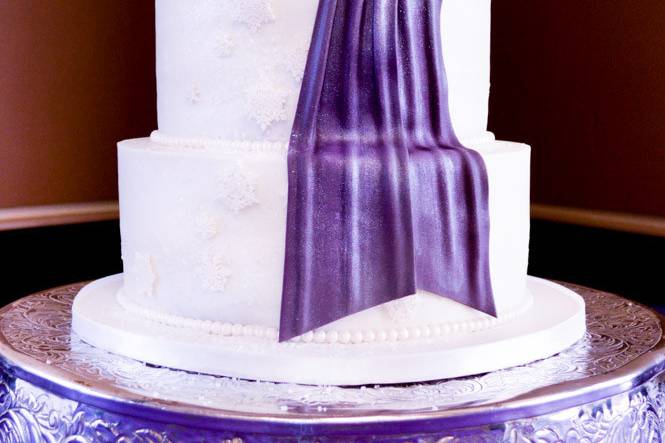 Winter wedding cake with snowflakes and purple sash