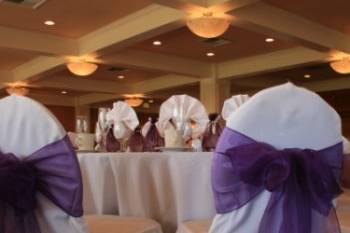 Beautiful white chair covers with Regal Purple bows in a country club setting.