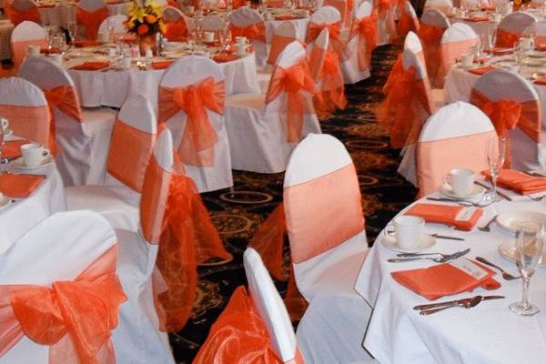 White chair covers with Orange organza bows.