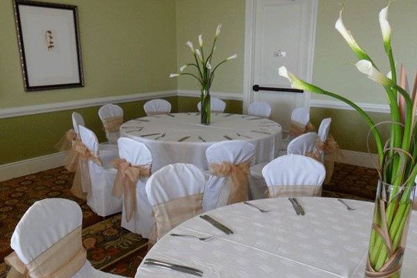 White chair covers with gold organza bows.