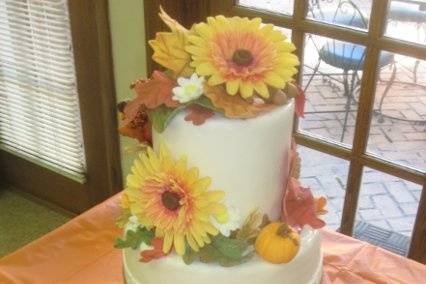 Round, stacked tiers, with double height, iced in buttercream and covered with fondant...featuring all edible flowers, leaves, pumpkins, acorns, and pinecones.