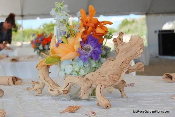 Sunset shade centerpiece with lilies, hydrangea, scabiosa & grapewood accent. Perfect for your beach wedding!