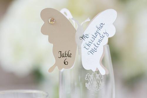 Butterflies at the top of champagne glasses for escort cards