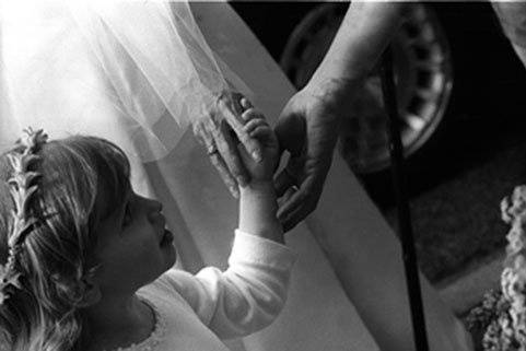 Bride, Flower girl and Grandma reach to hold each other's hands.  Symbolic image caught while in motion.  Right place, right time with the right photographer.