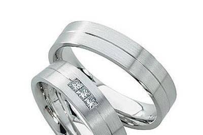 This 14k white gold flat surface wedding band has a matte finish with a shiny parallel cut through the center. Her wedding band is set with  3 brilliant 0.05 carat princess cut diamonds. Total diamond weight of approximately 0.15 carats. Comfort fit interior completes this classic best seller. Available in any size and width.