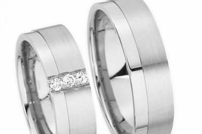 This 14k white gold flat surface wedding band has a matte finish with a shiny parallel cut through the center. Her wedding band is set with  3 brilliant 0.05 carat princess cut diamonds. Total diamond weight of approximately 0.15 carats. Comfort fit interior completes this classic best seller. Available in any size and width.