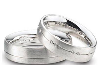 This 14k white gold his and hers wedding band set has a matte finish with a shiny parallel cut through the center. Comfort fit interior complete this classic best seller. Her wedding band is set with brilliant 0.01 carat round diamonds, weighing a total of approximately 0.24 cts.