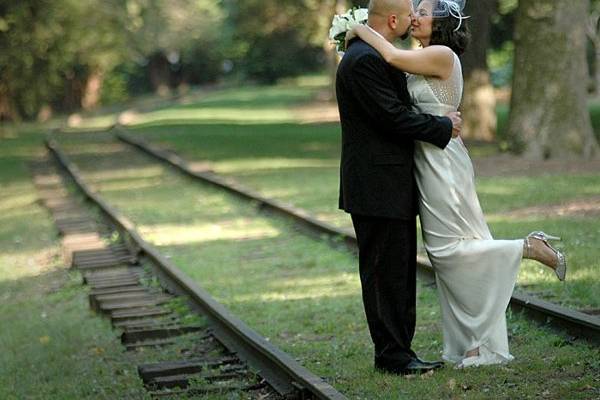 Bride and Groom kissing on railroad tracks.