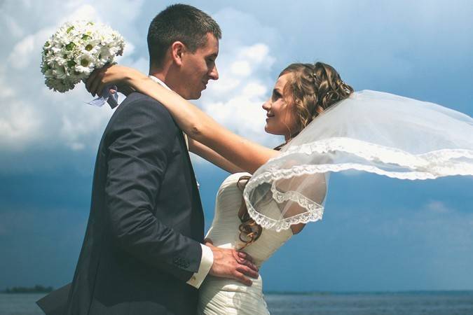 The nautical bride and groom, with the winds of the water elegantly swaying that veil to the side.