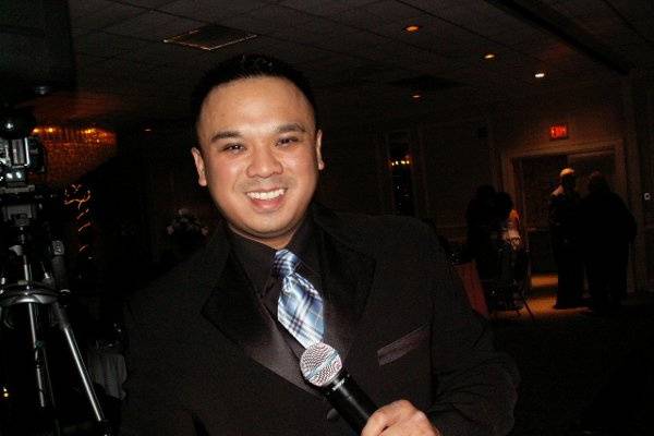 Blue Burberry Tie, Shure microphone, DJ Chris Andres, a Filipino Wedding DJ in New Jersey, provides quality DJ entertainment for all events using uplighting, intelligent lighting, video montages, plasmas, photobooths and utilizes his talent entertaining guests with linedancing or linedances that people are familiar with.  Hire him as an MC or Emcee with his complete DJ entertainment package.