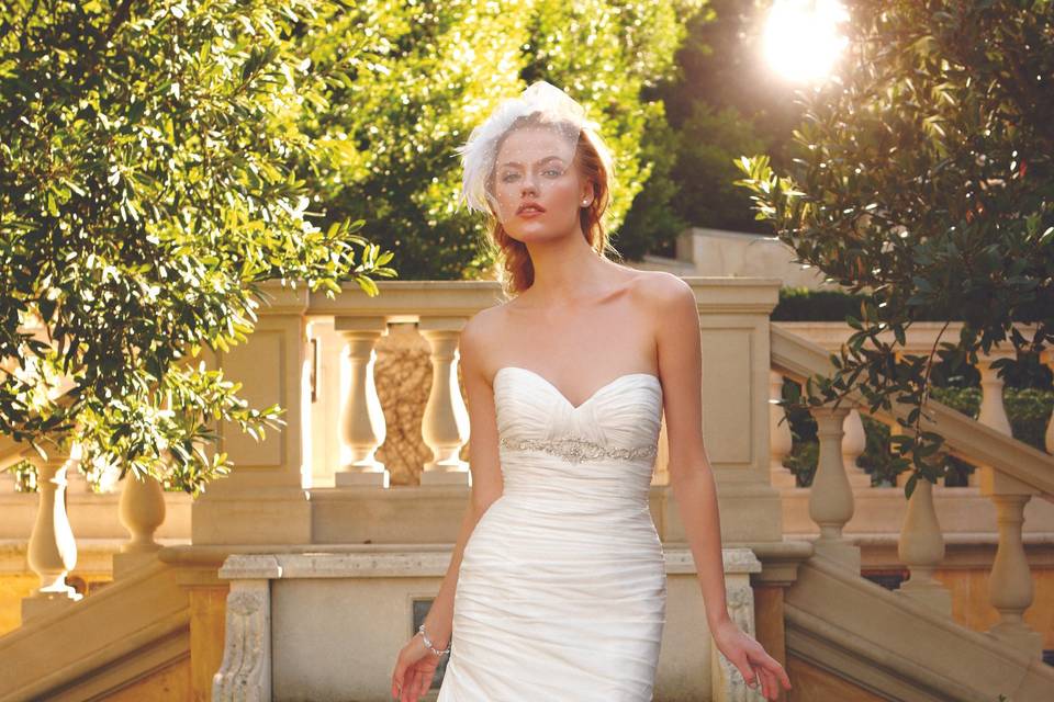 Style 2041 <br> Layers of Soft Tulle over Parchment Organza with Swarovski Crystal and Freshwater Pearl appliqué band accented with pleated sweetheart neckline and crystal buttons on the bodice.