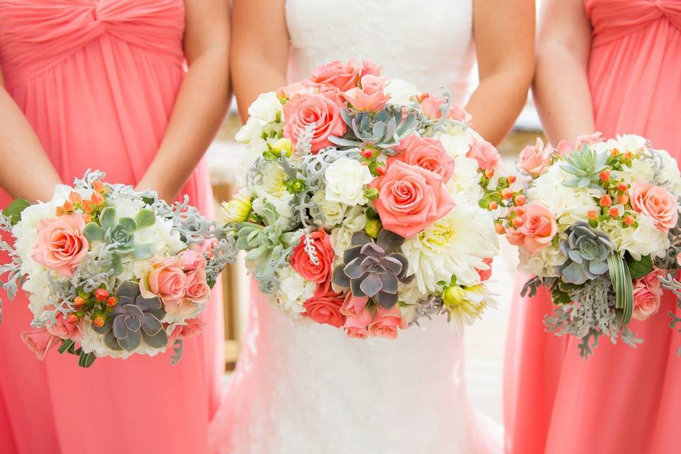 Coral roses and echeveria star in this hdntied bouquet.