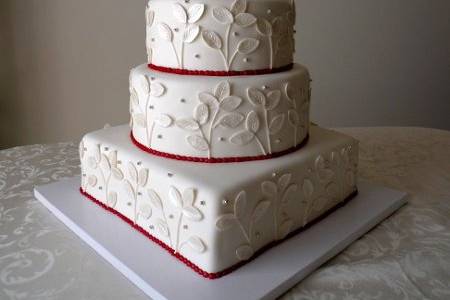 Elegant white fondant cake with luster leaves and silver dragees with red borde