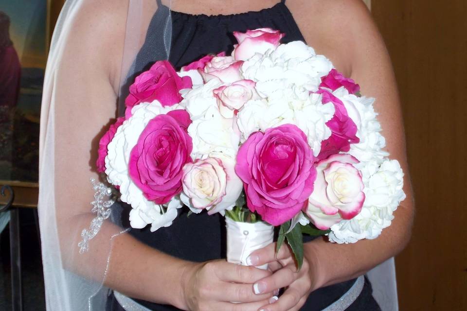 Open roses and a smiling bride it doesn't get much better.  This beautiful classic hand tied bouquet that is rich in color with hot pink and pink tipped roses artfully arranged in a bed of white.