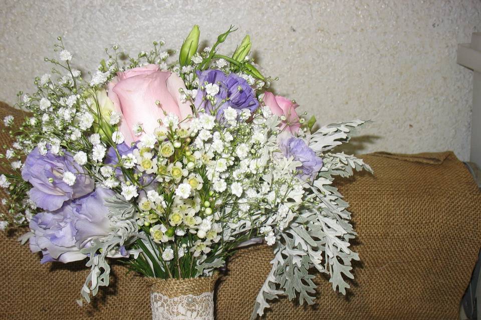 A bridal bouquet created with roses, lisianthus and babysbreath and fringed dusty miller
