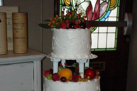 Three tiered column bettercream with scroll design accented with fresh fruit. Reception held at J Mac's Restaurant on St. Simons Island, Ga.