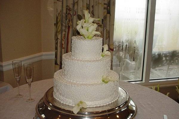 Three tier buttercream with lace design accented with calla lilies. Reception held at Epworth By The Sea on St. Simons Island, Ga.