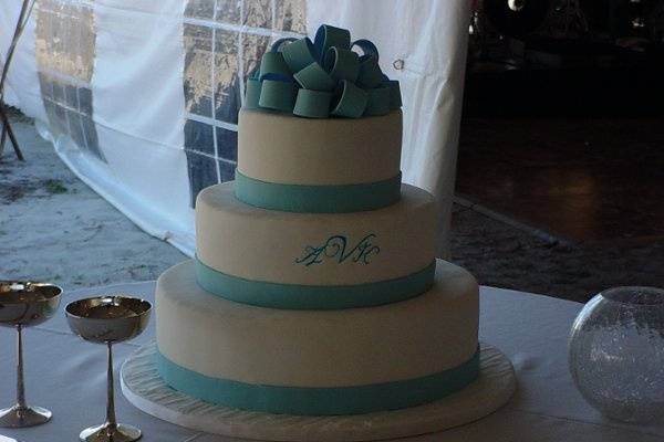Three tier fondant covered wedding cake with fondant bands and bow.