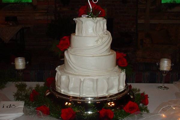 Four tier buttercream with fondant drapings and a pair of doves accented with red roses.