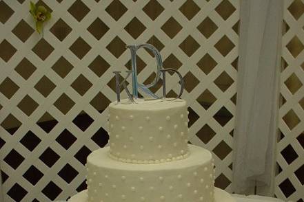 Three tier buttercream with dots, accented with white and red roses.