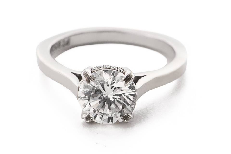This solitaire engagement ring is slightly modern with a diamond pave basket in platinum.