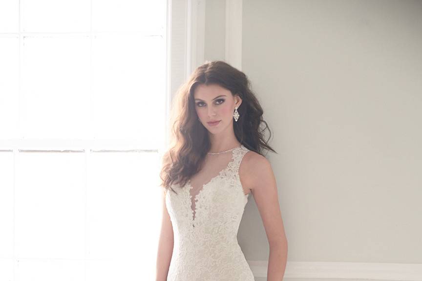 Style MJ156 <br> This structured lace gown features a deep v-neck softened by illusion net at the bodice and back.