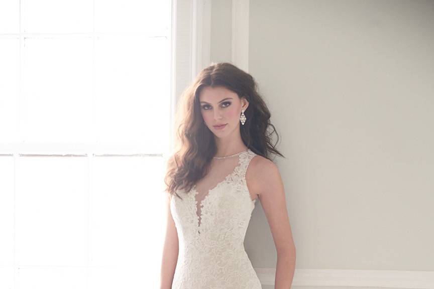 Style MJ155 <br> Textured lace embroidery trails down this gown to a dramatic ruffled skirt.