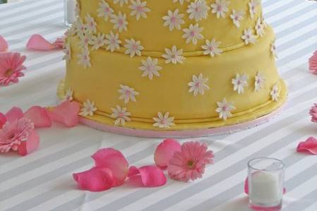 Three tier wedding cake, half chocolate silk and half french vanilla, with buttercreme frosting and filling, covered in pale yellow homemade fondant and over 250 gumpaste daisies!
