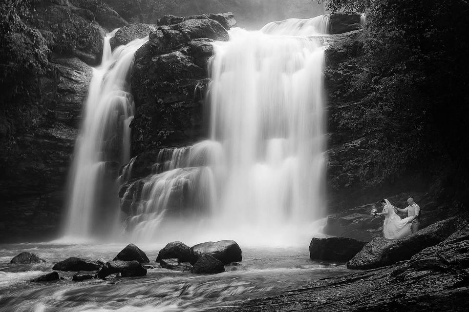 Couple dwarfed by waterfall