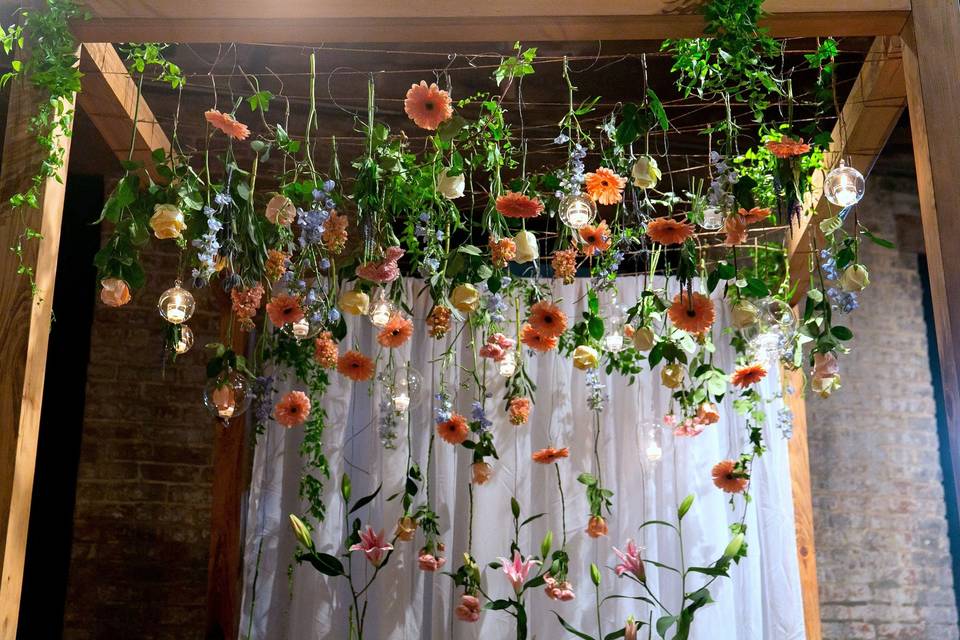 Custom wooden chuppah with hanging gerber a daisies, roses, thistle & stock at the Chicory