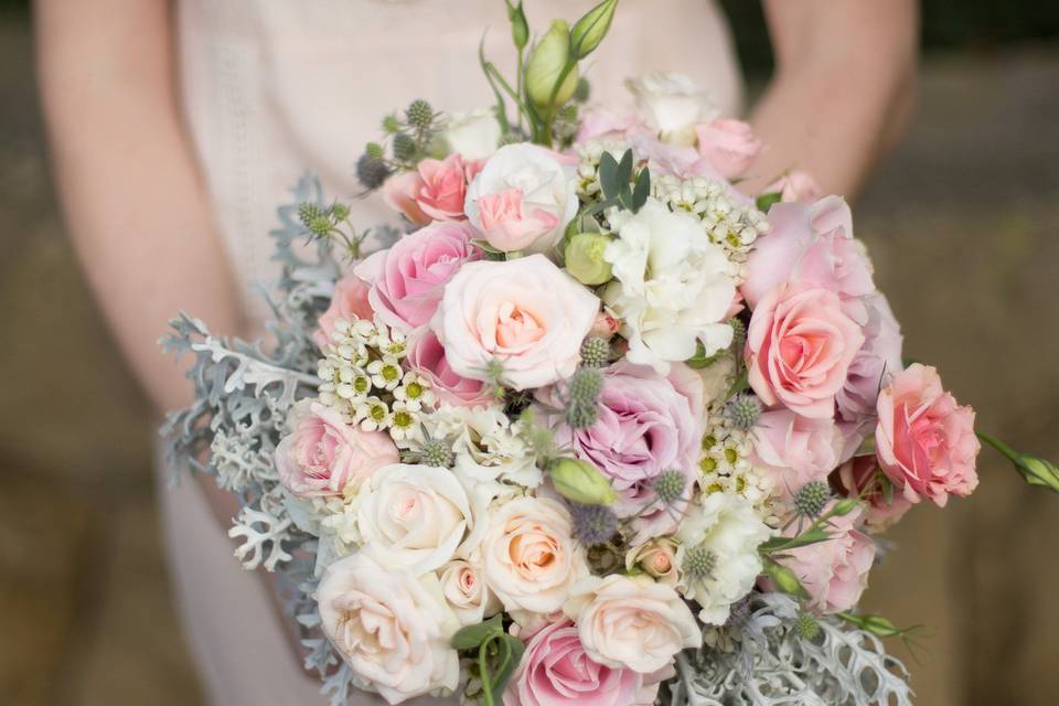 Subtle pastels in pinks and Ivory with roses, lisianthus, and dusty miller.