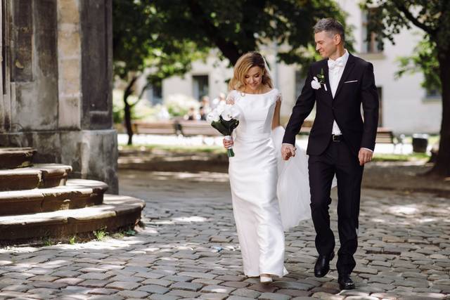 vecteezy_groom-holds-bride-s-hand-while-walking-on-cobblestone-path_1421324.jpg