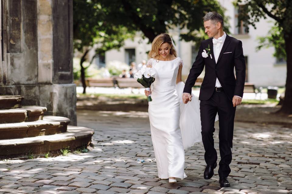 vecteezy_groom-holds-bride-s-hand-while-walking-on-cobblestone-path_1421324.jpg
