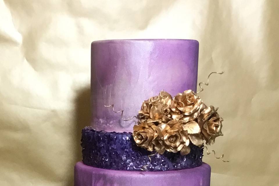 This 2-tone purple cake is an over the top cake with 5 tiers, and the cluster of gold roses and accents, and sparkley darker purples tiers.
