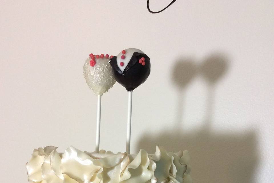 A close up of the bride and groom cake pop toppers all decked out and ready for the big day.