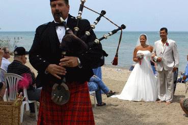 A surprise piper for the bride. Leading the newlyweds off the beach.
