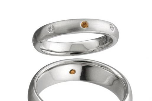 Matching bands for him and her accented by a rare dark orange diamond.