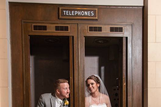 Bride and groom posed in old phone booths