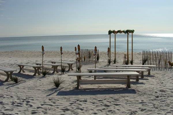 Natural bamboo arch with white canopy and flowers and seating for 40 completes this beach scene.