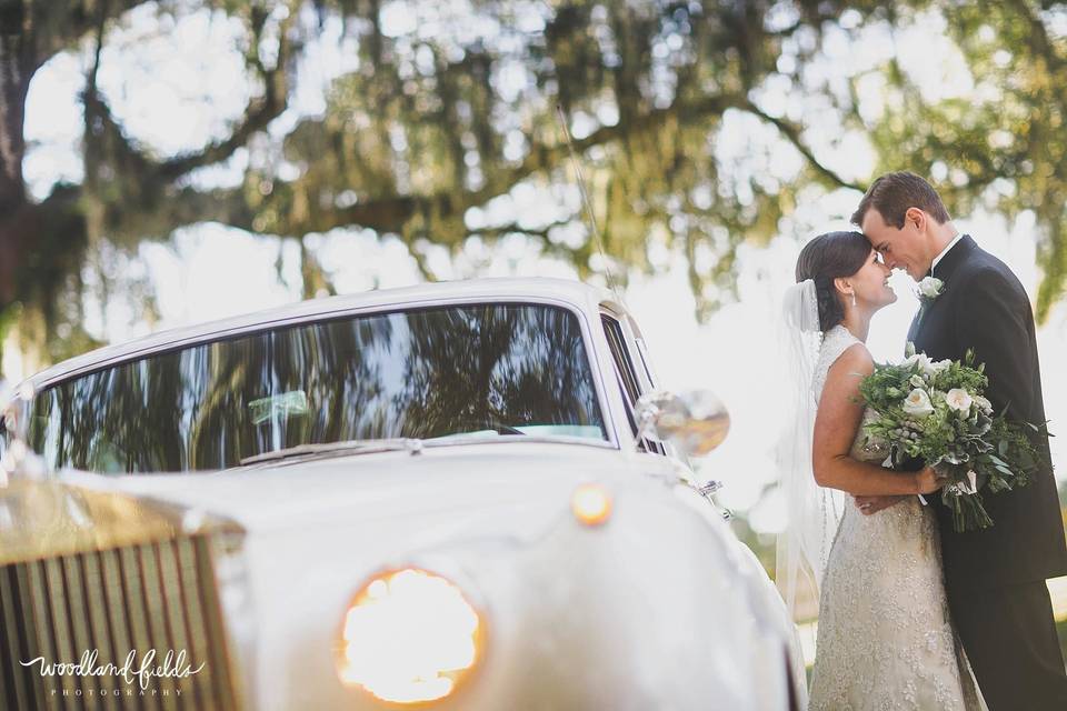 Newlyweds by their wedding car