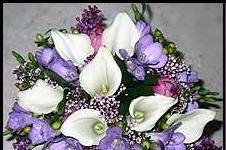 Spring bridal bouquet of calla lilies, freesia, lilac, tulips, and berries.